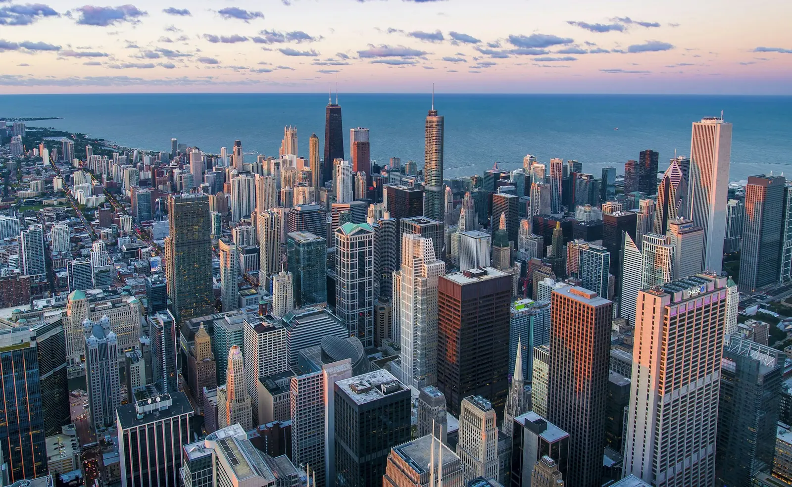 A city skyline beyond a dark river at dusk
