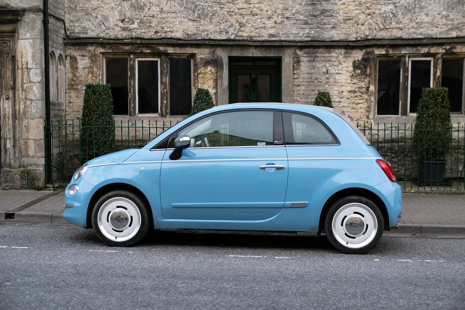 A small blue city car parked on a residential street