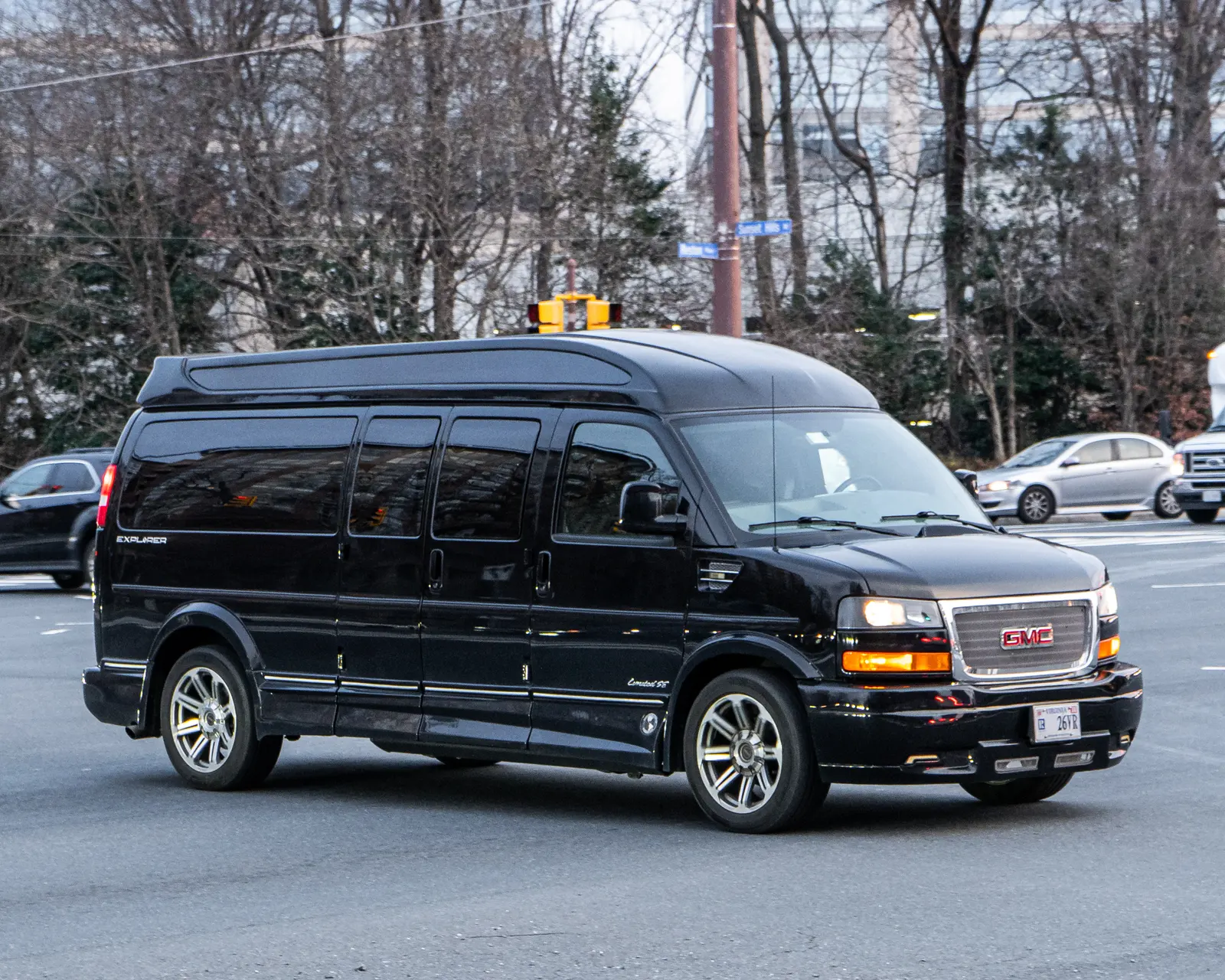 A dark passenger van with a long row of side windows