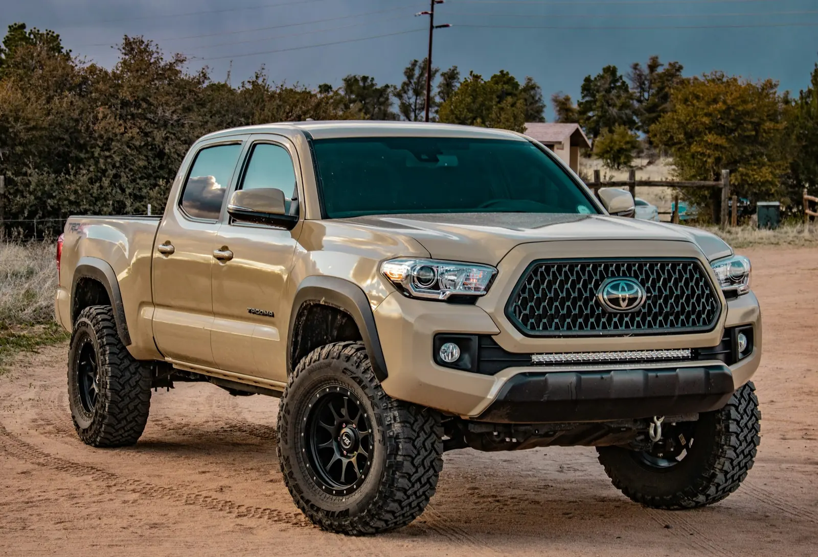 A tan pickup truck parked on a dirt lot