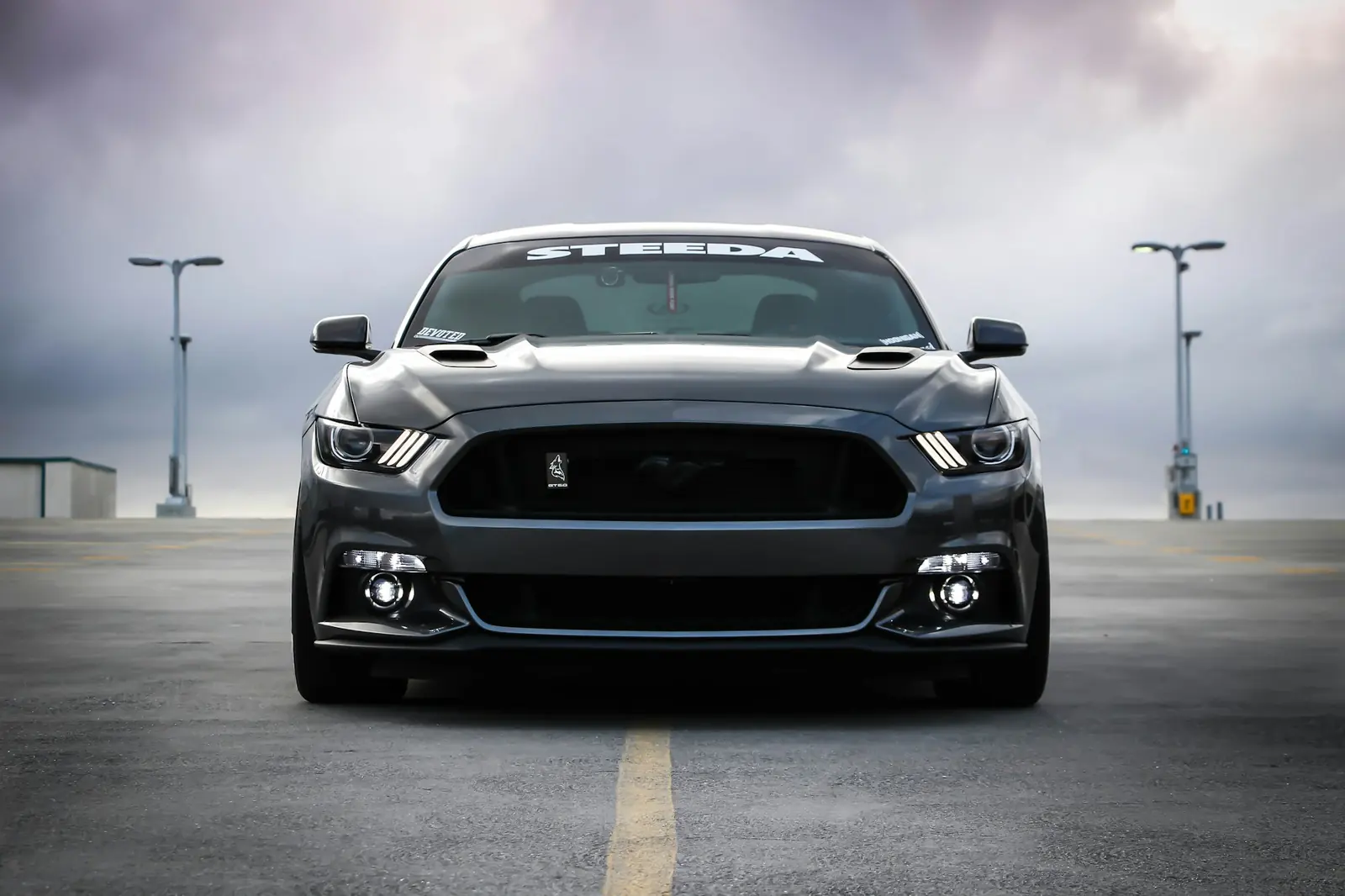 A dark performance car facing the camera on an empty road