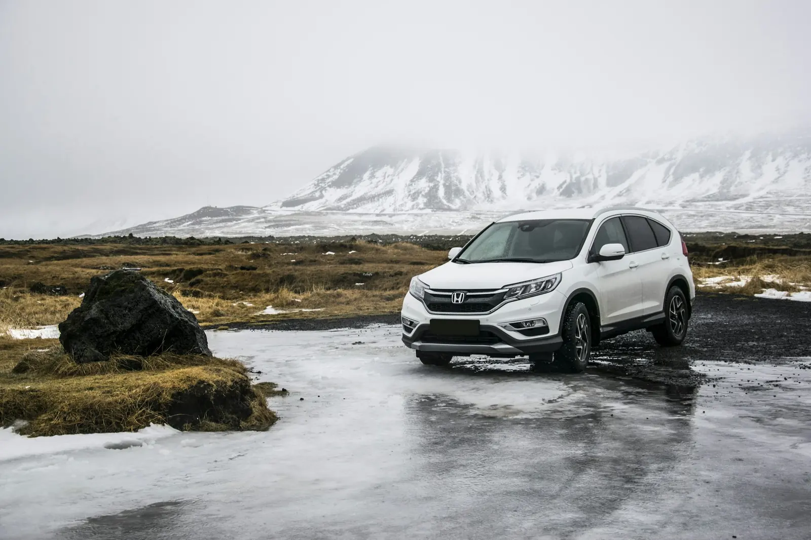 A white SUV parked on a frozen plain with mountains behind it